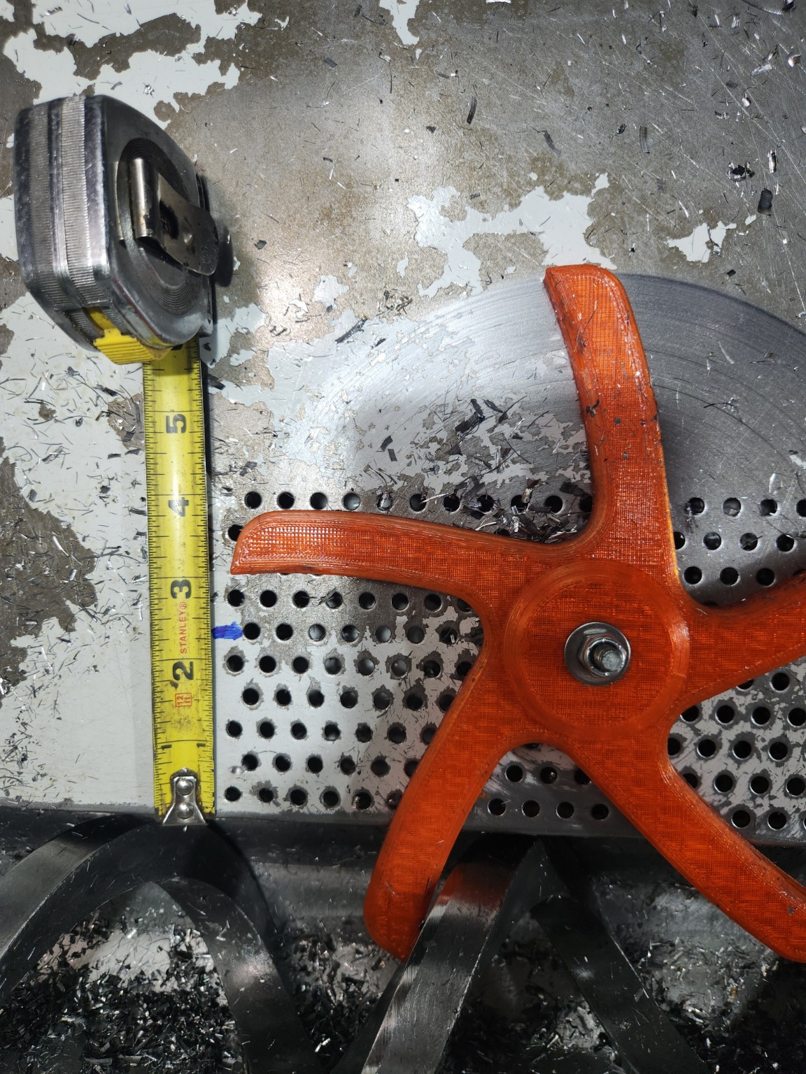 Tape measure showing the required chip-pan mounting-hole row location beside the auger