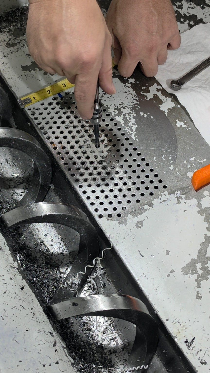 Tapping the selected chip-pan mounting hole with a 1/4-20 tap